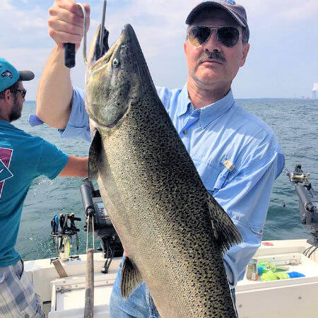 angler from Catfish Creek NY holding up a large king salmon on Lake Ontario charter trip