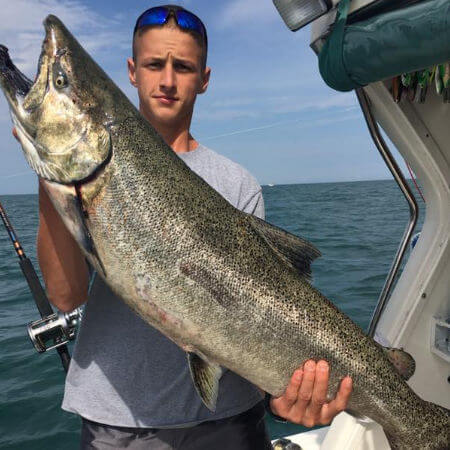 young man from Henderson NY holding up a Lake Ontario king salmon