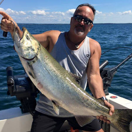 man shows off his mid-summer brown trout on an afternoon on a port of oswego charter trip