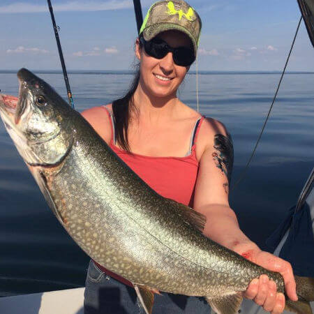 pretty lady in ball cap holds up her Lake Ontario king salmon