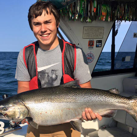 young angler displays a nice afternoon charter king salmon