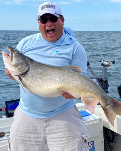 Happy Midway Charters angler lets out a yell as he holds up huge lake trout.